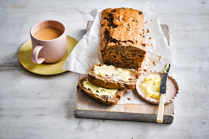 A bara brith loaf with two buttered slices