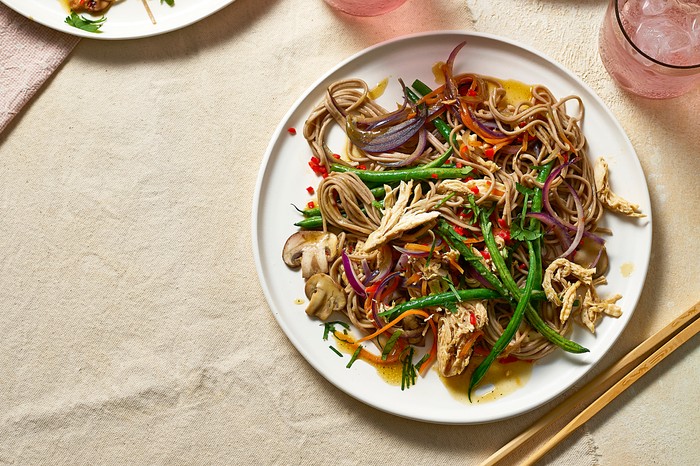 Three plates of colourful stir-fry with drinks on the side