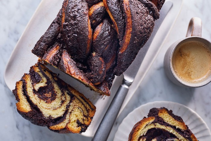 Loaf marble cake on a plate with a slice cut out and a slice on a circular plate next to a tea
