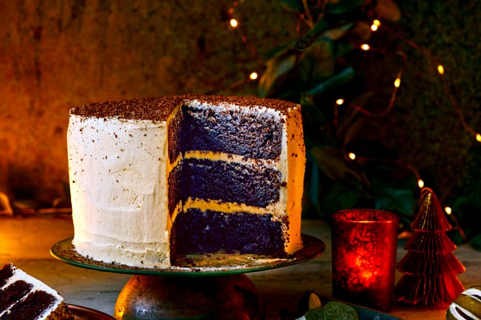 An impressive three-layered iced chocolate cake with fairy lights in the background