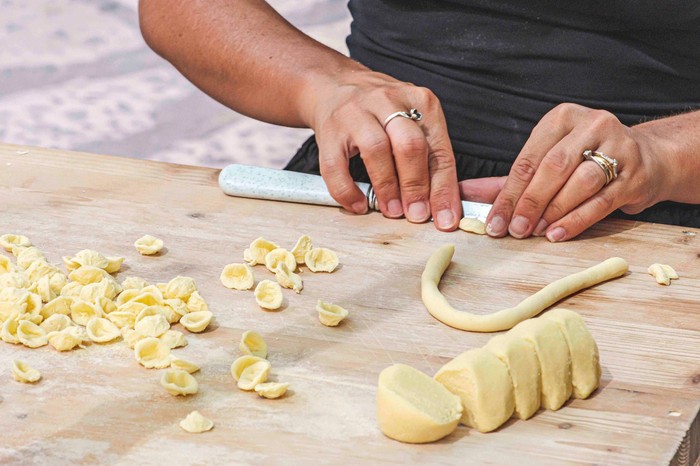 Local woman preparing in the street of Bari old town orecchiette or orecchietta, made with durum wheat and water, handmade pasta typical of Puglia or Apulia, a region of Southern Italy, close up