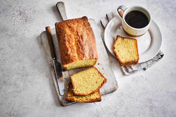 A sliced pound cake with coffee on the side