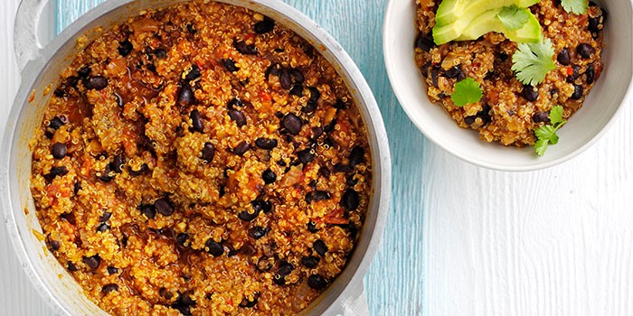 Two bowls of quinoa & black bean chilli on a blue and white background