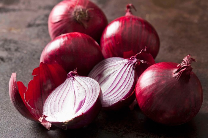 Rote Zwiebeln (Allium cepa), ganze, Hälften, dunkler Untergrund