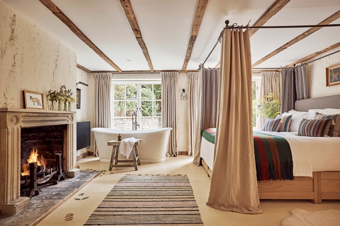 A wood-beamed room decorated with sheepskins, woollen rugs and quilted blankets