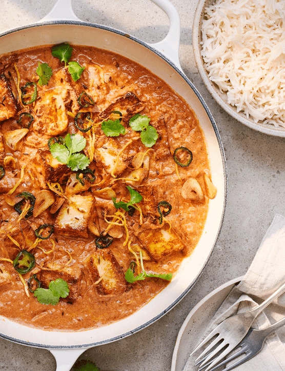 Halloumi curry in a big bowl with a bowl of fluffy white rice on the side