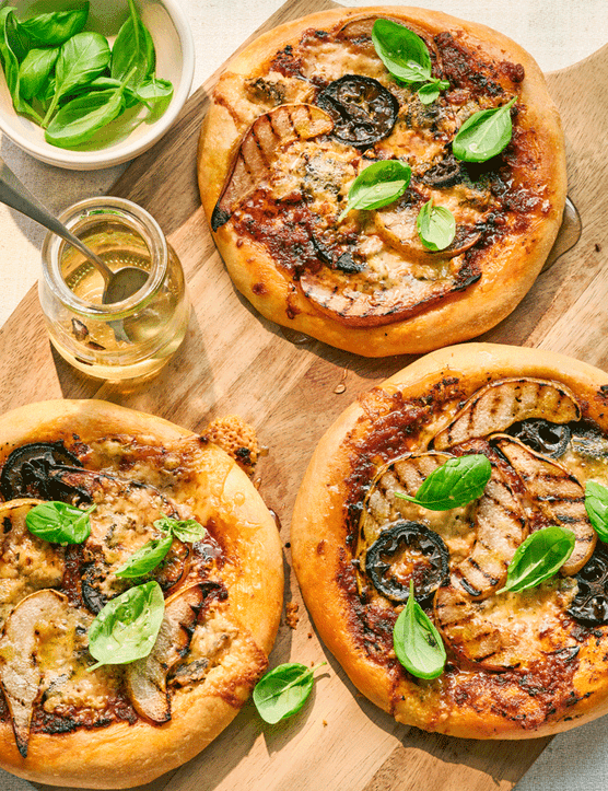 Three pear, gorgonzola and pickled walnut pizettes on a wooden board